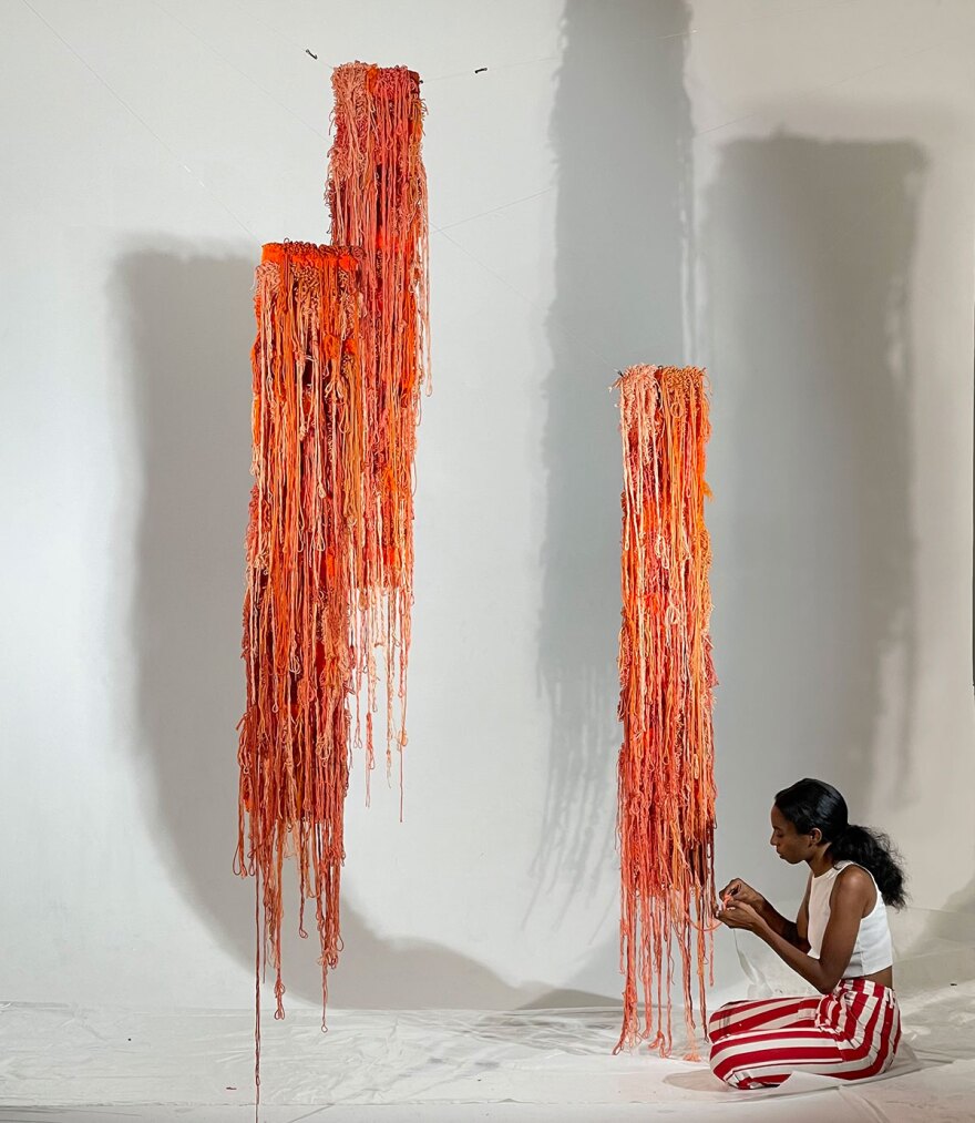Artist Denja Harris is shown working on a fiber art installation at Intervals Gallery in 2023.